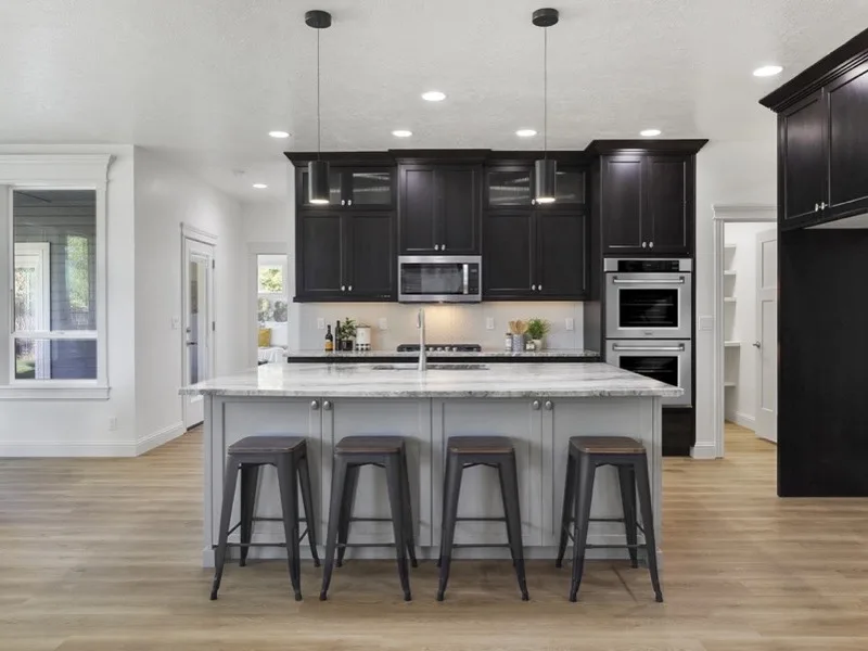 Remodeled kitchen with marble-top island, dark cabinets, and pendant lighting